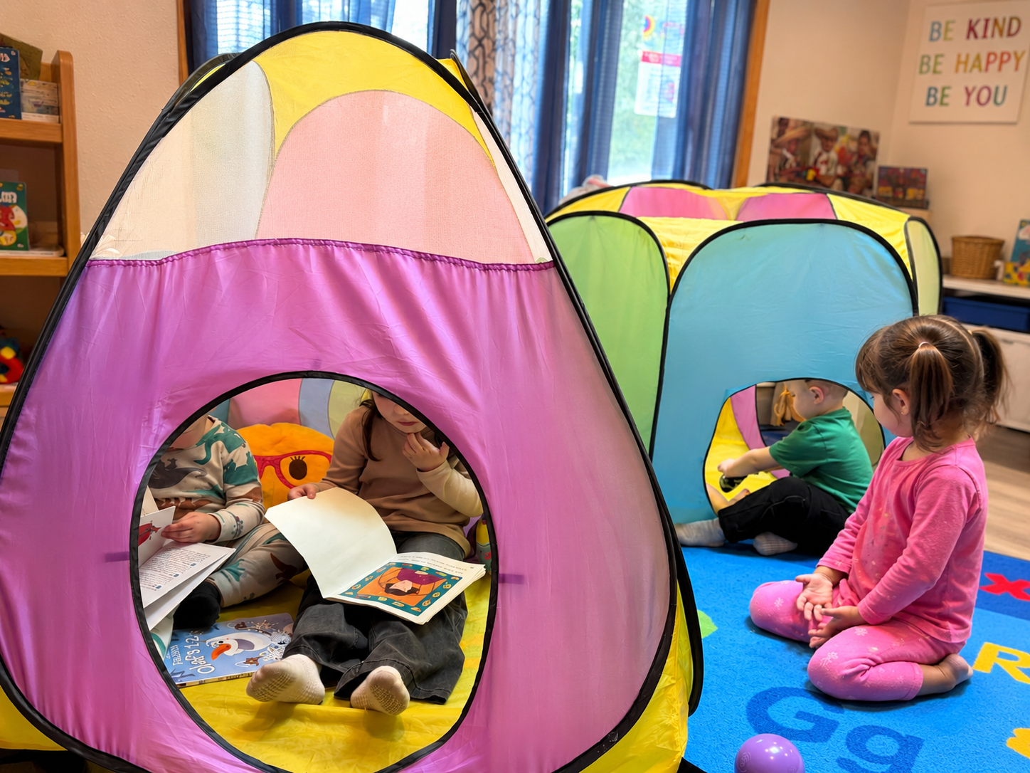 Children reading and playing in colorful indoor tents